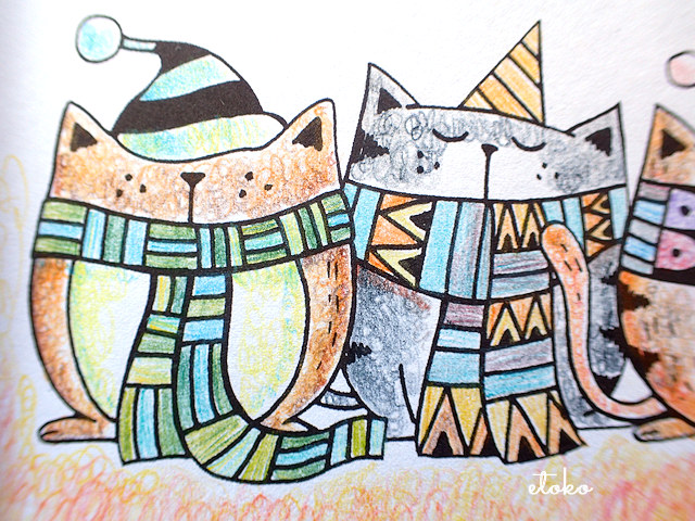 寒色系のマジックペンシルでマフラーと巻いて帽子をかぶった猫たちを塗っている