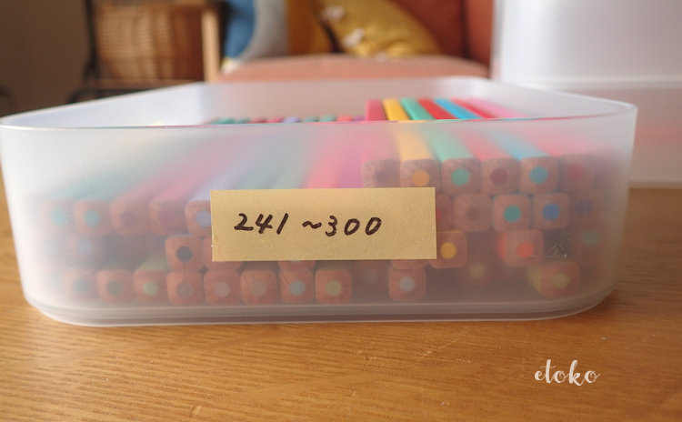 ダイソーの積み重ねボックスに色番号を書いたテープを貼りつけ、番号に対応したフェリシモの500色の色えんぴつを入れている
